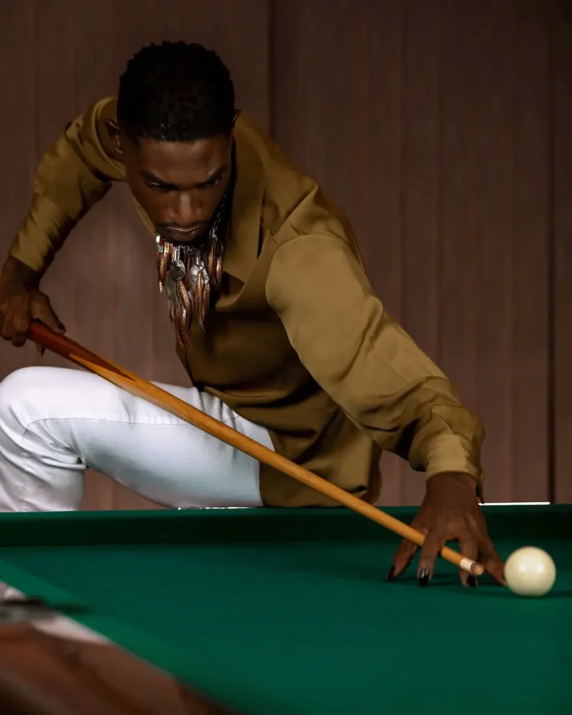 Male model directing a billiards cue toward the camera in a planned fashion portrait