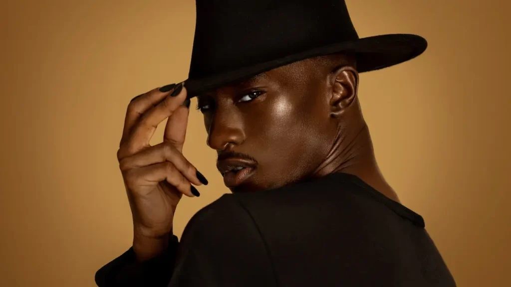 Male model adjusting a black hat in the final Show Stopper campaign portrait