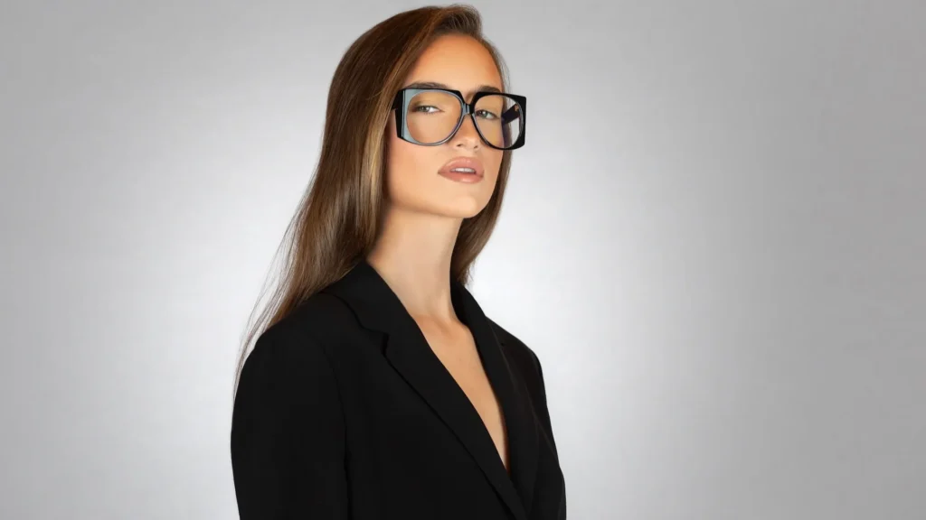 Oversized black statement glasses photographed with a tailored black blazer.