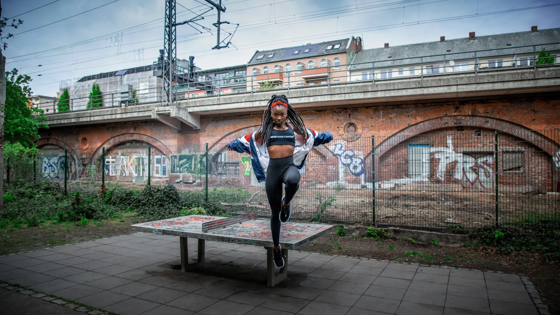 Female athlete posing on a concrete table at a Berlin sports court