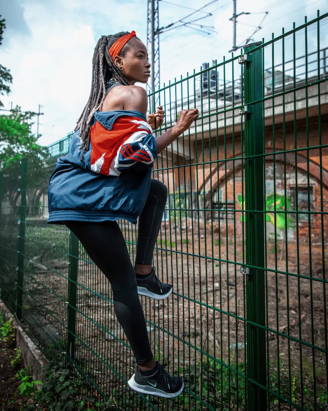 Female athlete climbing a metal fence in an urban Berlin sports setting