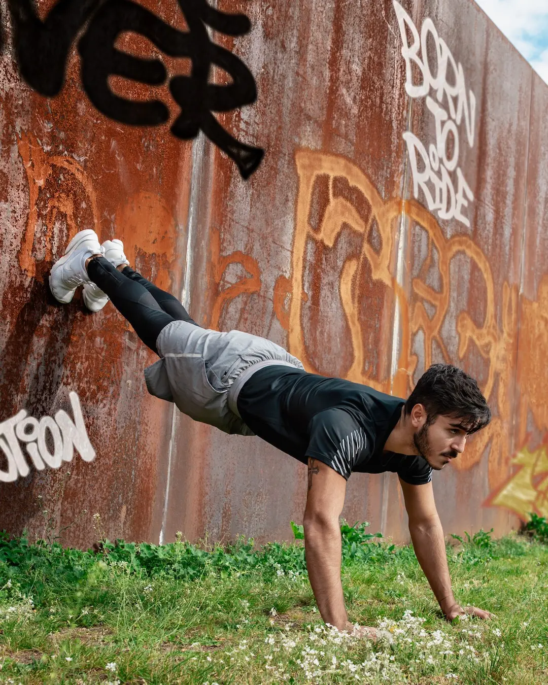 Athlete holding a controlled handstand beside a graffiti wall in Berlin