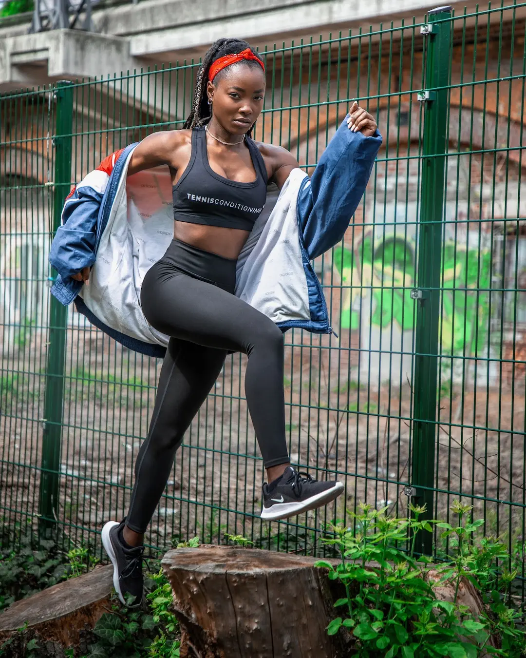 Female athlete stepping onto a tree stump beside a Berlin sports court