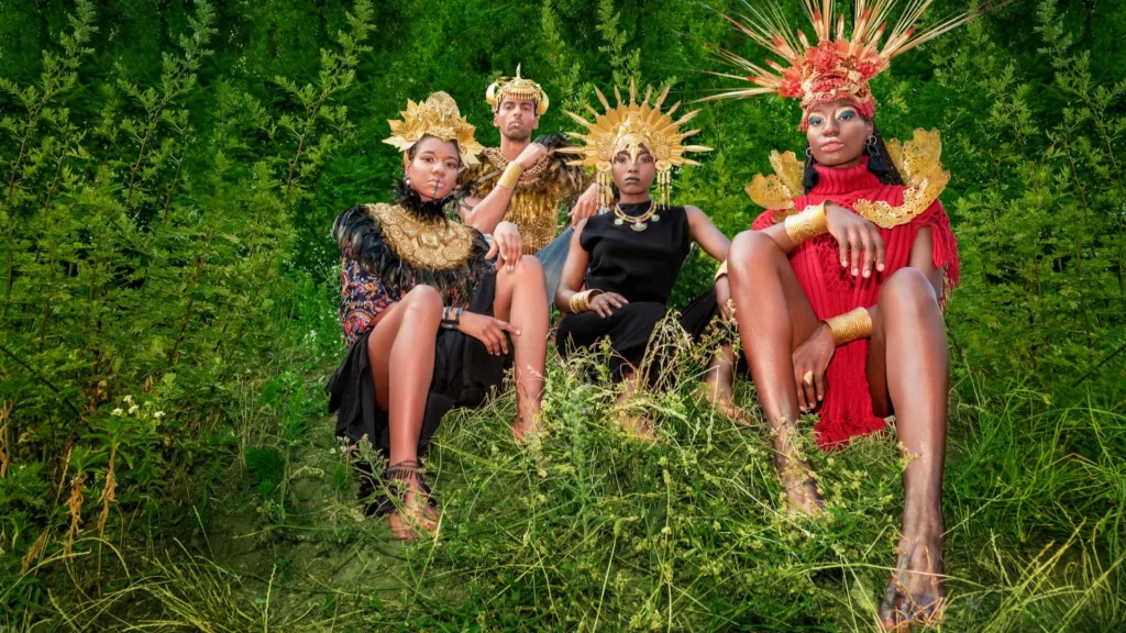 Fashion editorial cast posed in greenery with coordinated sculptural headpieces