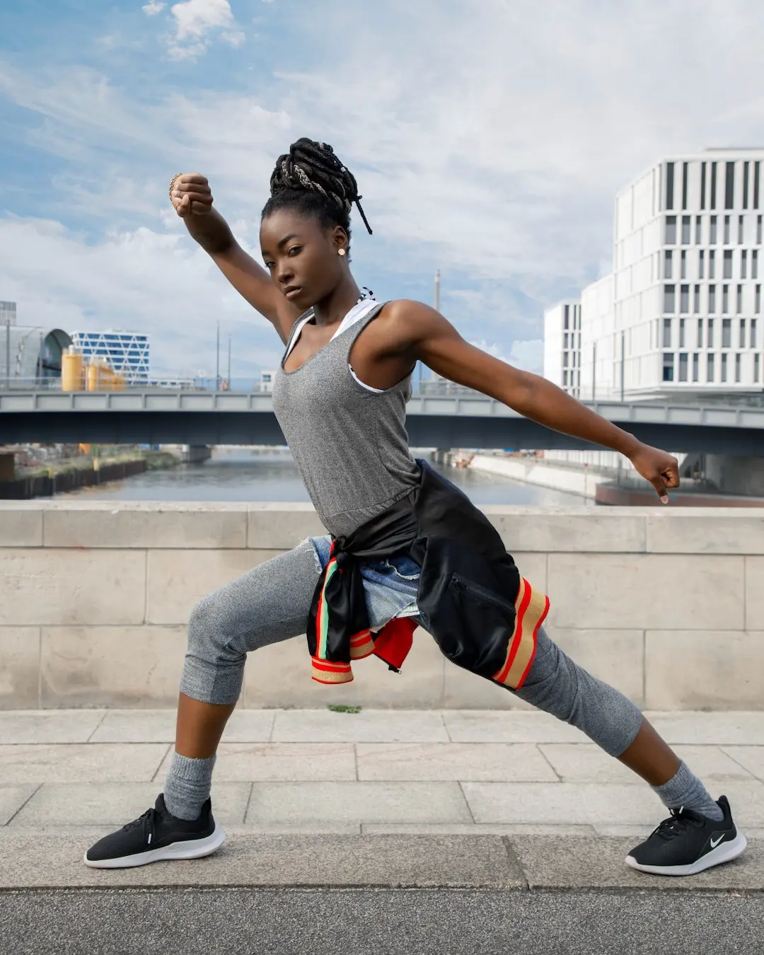 Female athlete stretching dynamically beside modern Berlin architecture