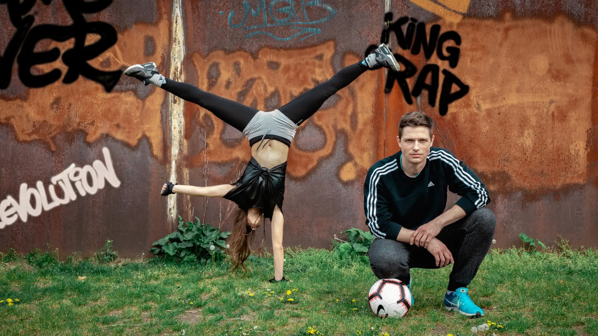 Football athletes posing and moving beside a graffiti-covered wall in Berlin