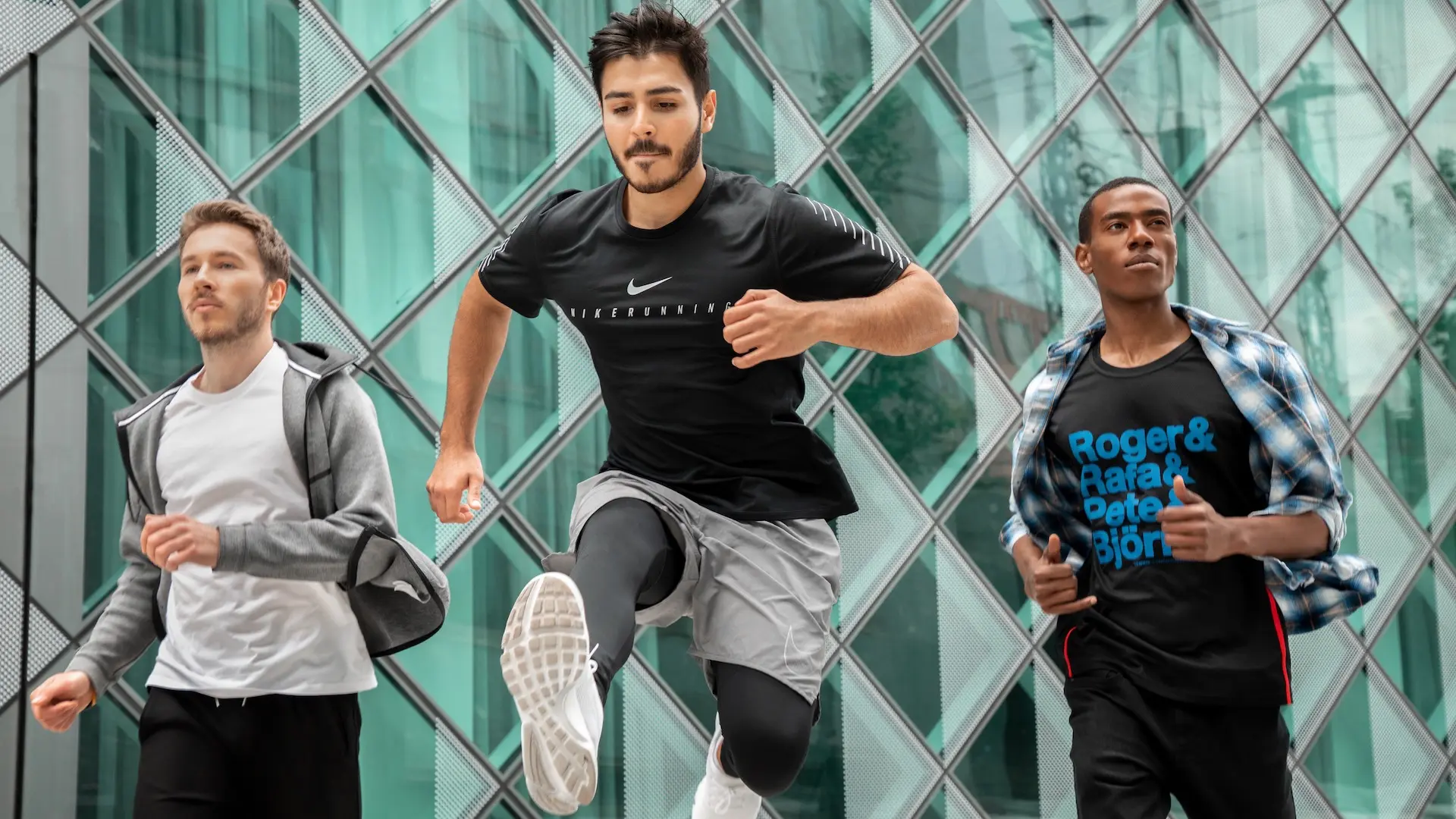 Three runners moving past modern glass architecture in Berlin