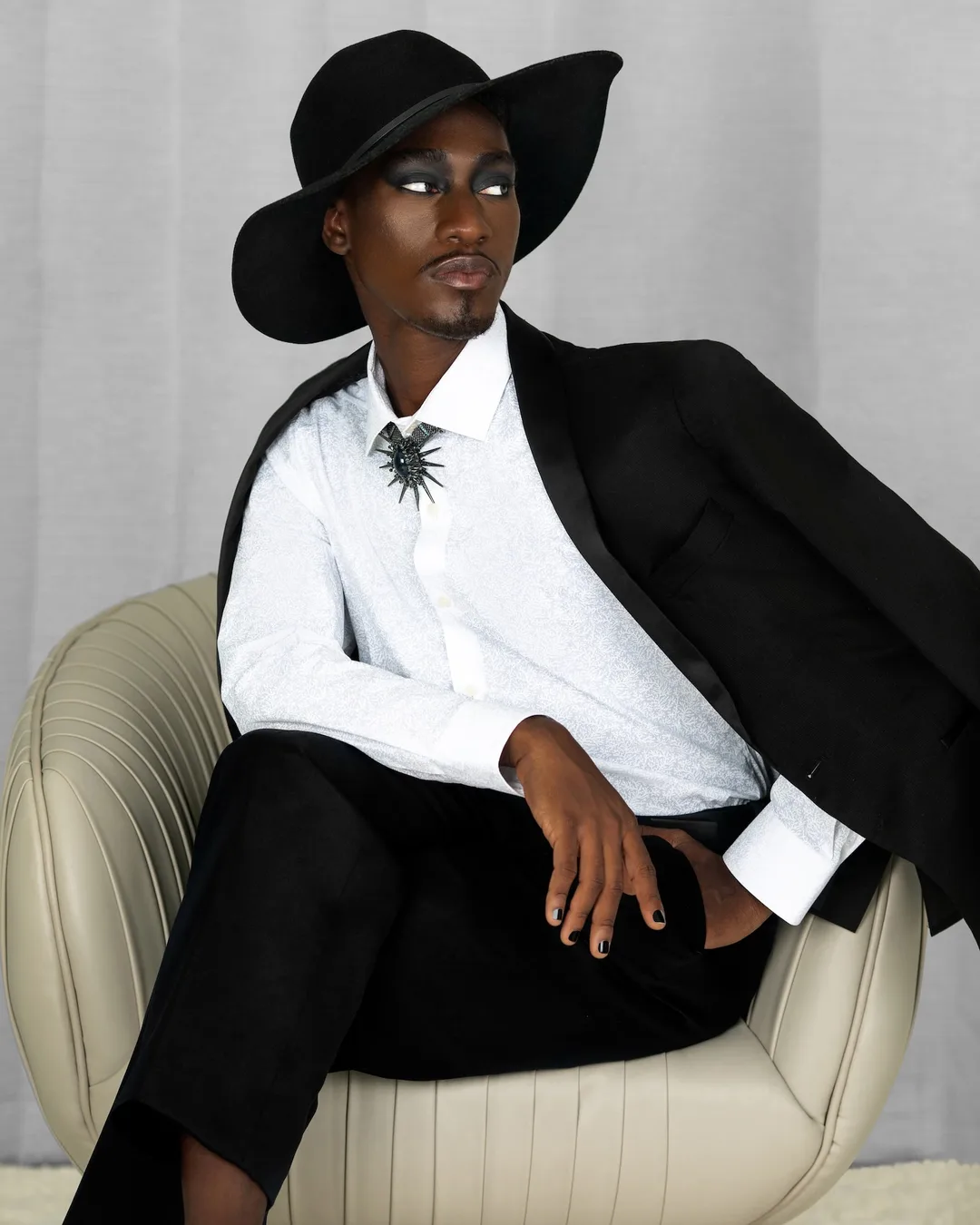 Troy wearing a black suit and wide-brim hat in a studio fashion portrait