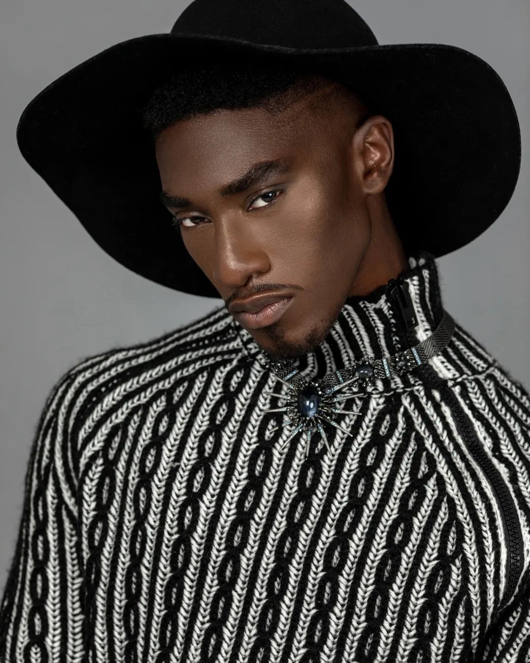 Troy in a black-and-white sweater and wide-brim hat