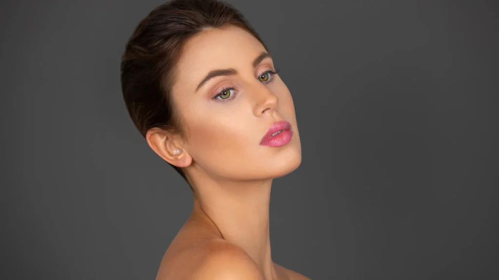 Close beauty portrait of Rebecca with soft pink makeup against a charcoal background