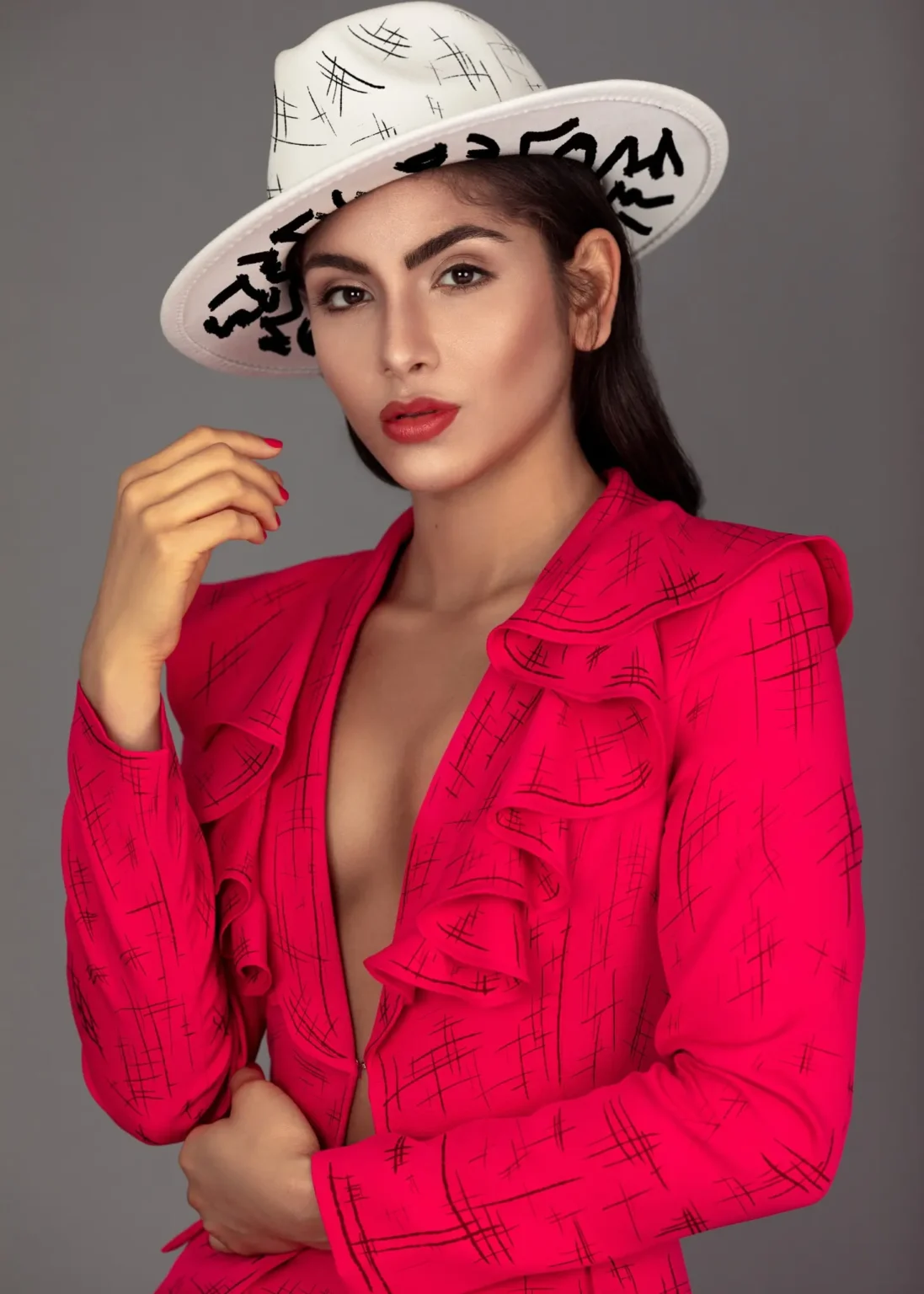 Close fashion portrait of Liany in a red suit and white graphic hat