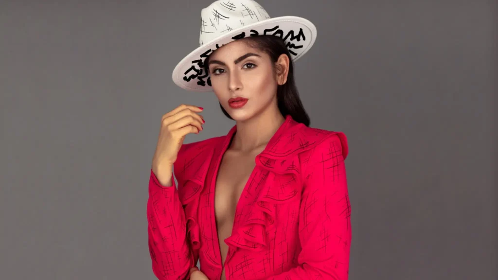 Landscape portrait of Liany in a vivid red Rare London suit and white graphic hat against a gray background