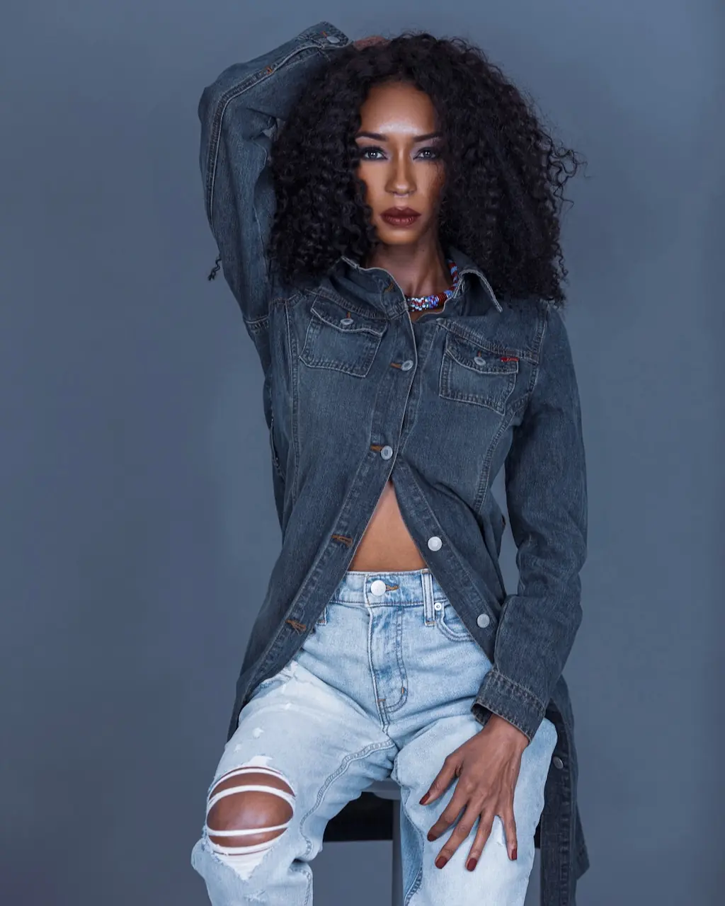 Studio Fashion Editorial Production: Simple Comforts - Phil Halfmann Jovona Logan seated in layered denim against a gray studio background.